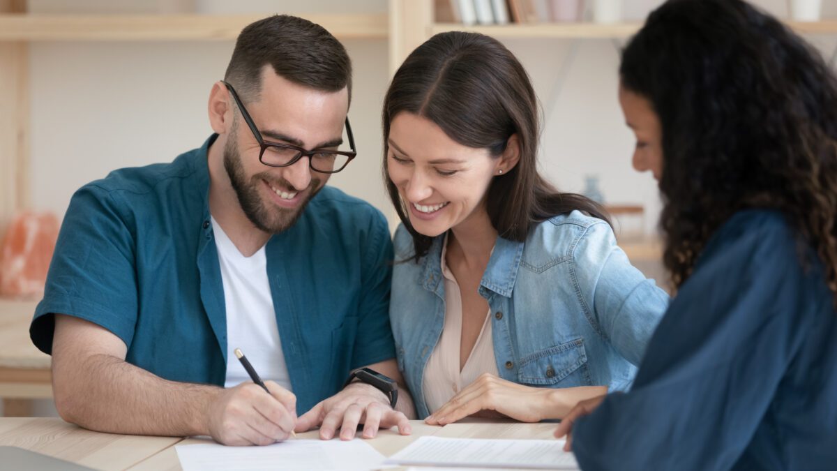 Happy family couple signing contract with agent.